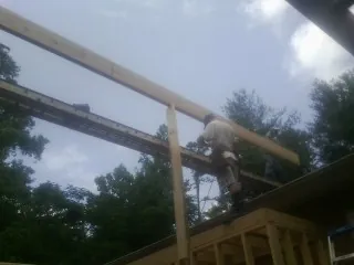 Carpenter setting a ridge beam over a new addition frame — Ice Dam Removal by Roofing Brothers in Mackinaw