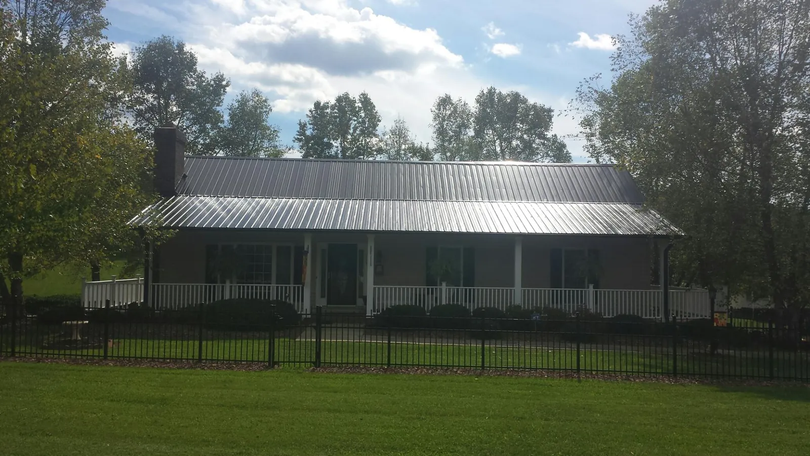 Gray metal roof on a brick ranch with a full width front porch — Gutter Guard Installation work by our crew in Mackinaw
